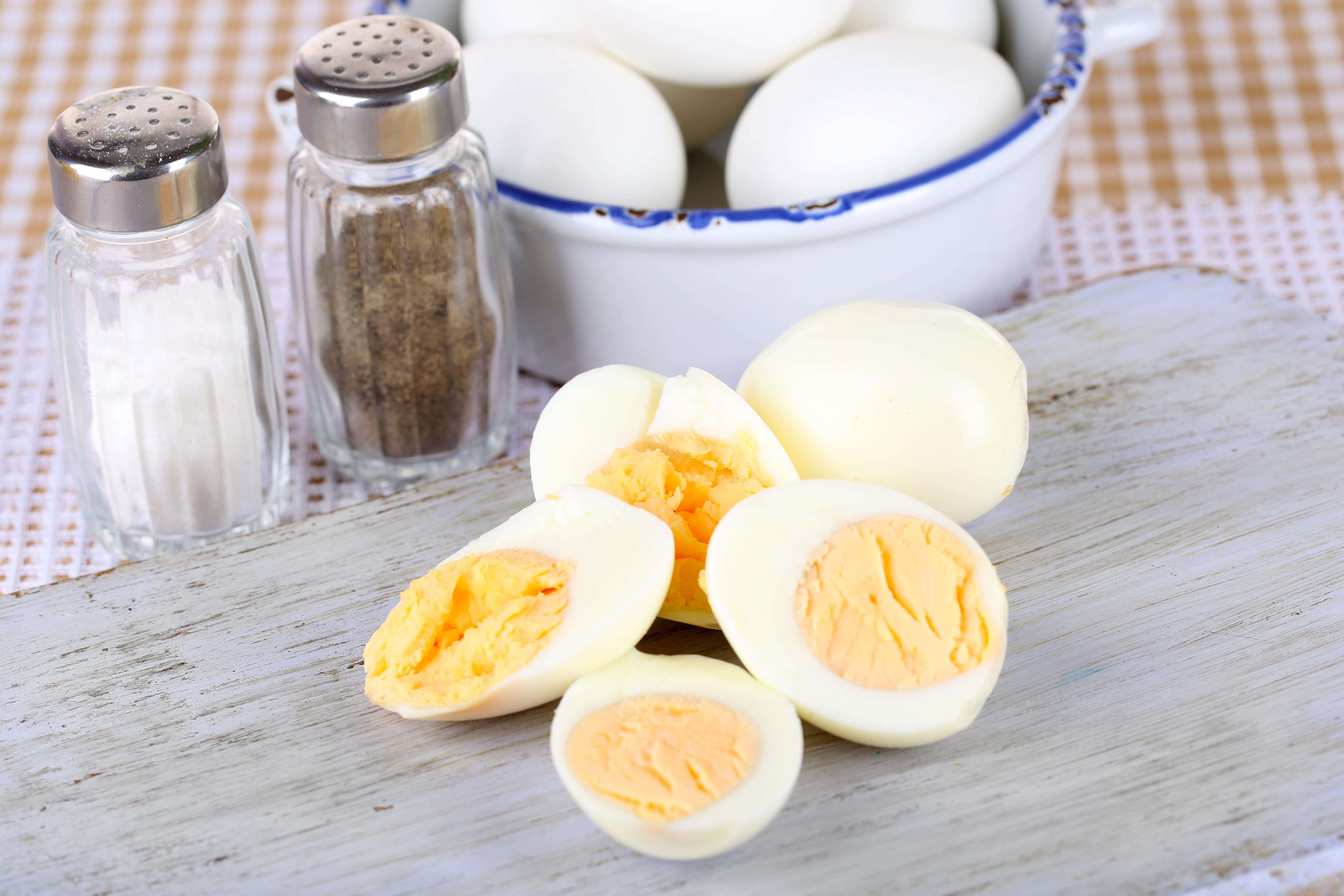 Boiled eggs on wooden board on tablecloth