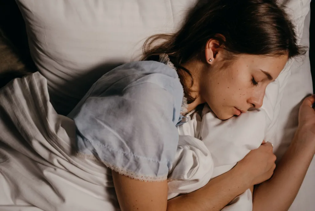 Jonge vrouw slaapt 's nachts rustig op een wit kussen in een donkere slaapkamer