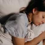 Jonge vrouw slaapt 's nachts rustig op een wit kussen in een donkere slaapkamer