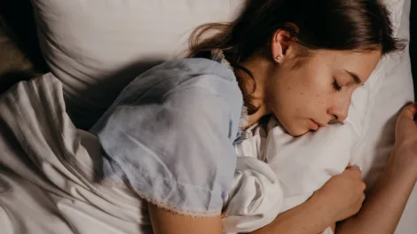 Jonge vrouw slaapt 's nachts rustig op een wit kussen in een donkere slaapkamer