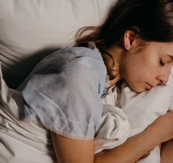 Jonge vrouw slaapt 's nachts rustig op een wit kussen in een donkere slaapkamer