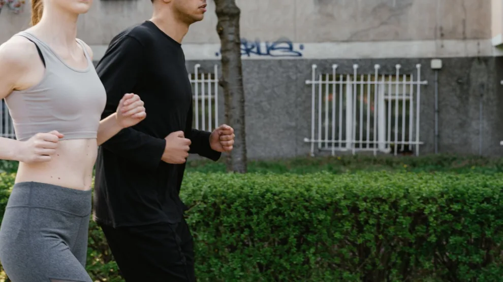 Man en vrouw joggen samen op een parkpad in het voorjaar, matige cardio die de afweer prikkelt